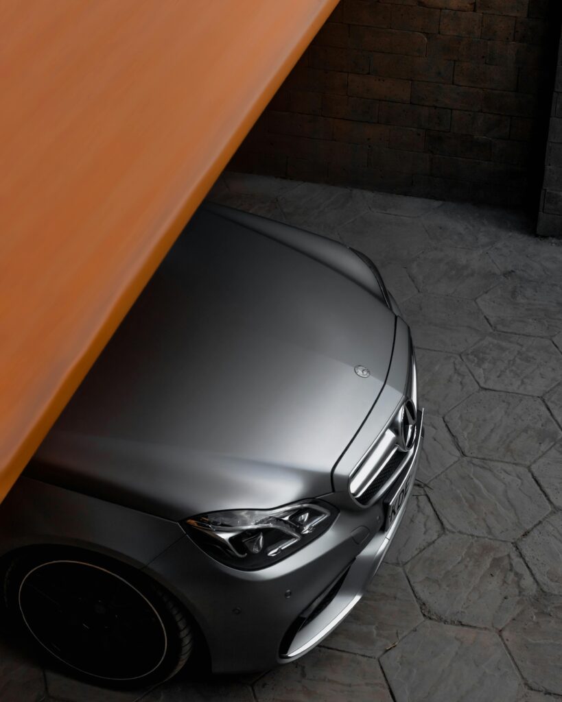 pexels-photo-12098554-12098554 Elegant silver Mercedes-Benz partially visible under a closing garage door.